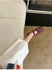 Close-up perspective of burgundy rhinestone mesh Mary Jane flat shoes worn on foot