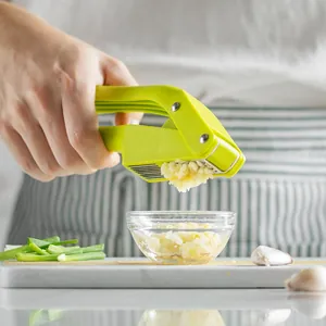 High-quality green manual 2-in-1 garlic press and slicer tool mincing fresh garlic into a bowl