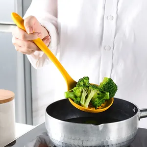 Mestolo forato in silicone giallo resistente al calore che solleva broccoli da una pentola