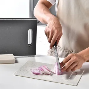 Planche à découper en plastique à motif marbré utilisée pour couper un oignon rouge