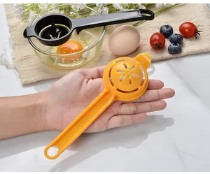 Detail view of a yellow plastic egg separator held in hand against kitchen props.