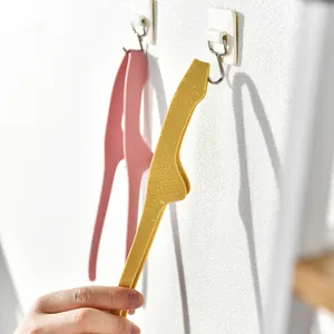 Yellow and pink horn-shaped silicone kitchen food tongs hanging on wall hooks for BBQ