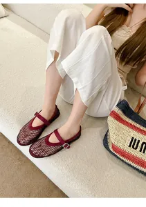 Close-up of elegant maroon mesh Mary Jane flats with buckle detail worn by a model in a room