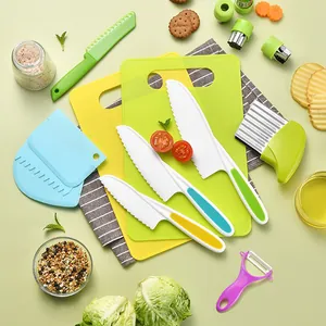 Colorful children's plastic kitchen knife set with cutting boards and peeler on green background