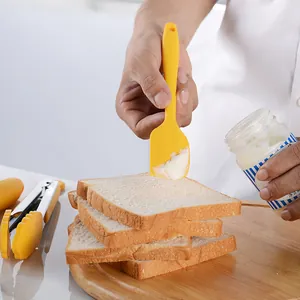 Professional yellow silicone baking spatula tool spreading cream on fresh toast slices
