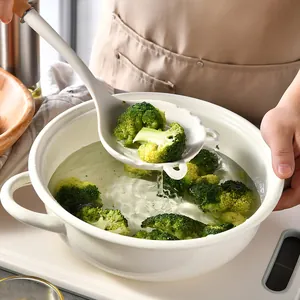 Professional white silicone slotted spoon straining fresh broccoli from a cooking pot