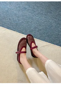 Close-up of burgundy mesh Mary Jane flats with sparkling rhinestone details on carpet