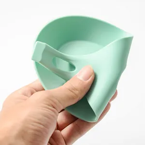 Flexible mint green silicone spoon rest kitchen tool being bent to show softness