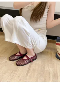 Detailed view of burgundy mesh Mary Jane flats with rhinestone accents on model.