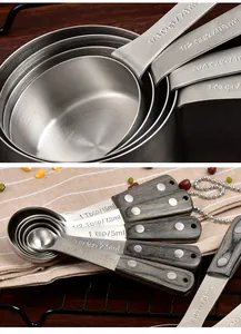 Close-up of stainless steel measuring cups and spoons with engraved units and wood handles.