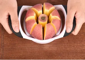 Close-up of stainless steel apple divider slicing a red apple into 8 wedges on a wooden table.