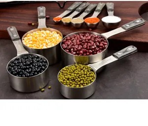 Detailed view of stainless steel measuring cups filled with various colorful beans and spices.