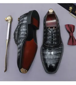 Macro view of men's crocodile pattern oxfords with red leather sole and metal tip.