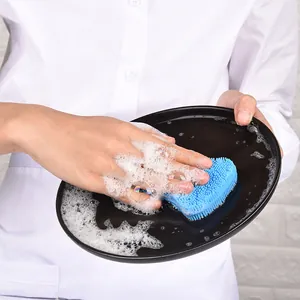 Ergonomic blue silicone dish brush cleaning a black ceramic plate with rich soapy foam