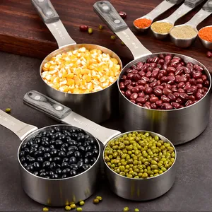 Stainless steel measuring cup and spoon set with wood handles filled with beans