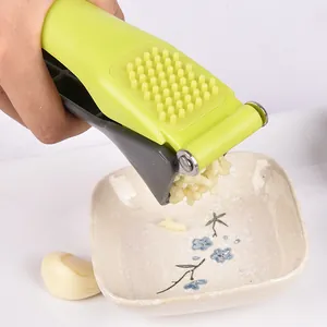 Durable green manual garlic press with ergonomic plastic handle for kitchen mincing