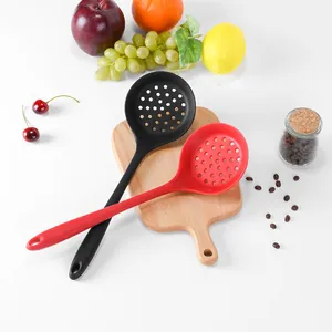 Heat resistant silicone slotted skimmer spoons in black and red on wooden board