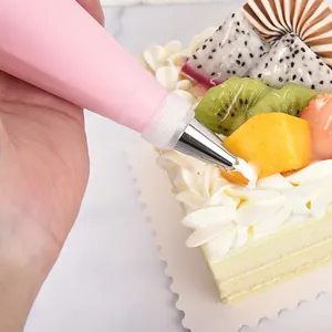 Pink reusable EVA piping bag with stainless steel nozzle decorating a fruit cake