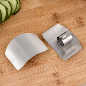 Stainless steel finger guards for safely cutting vegetables on a wooden board.