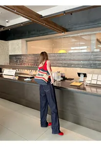 Full view of red Mary Jane flats styled with dark denim in a chic cafe interior