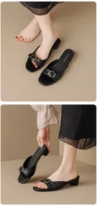 Detailed visual of retro black low-heeled mules featuring a stylish belt buckle design