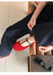 Detail shot of red suede Mary Jane flats with T-strap on model with denim pants.