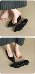 Macro view of black pointed-toe ballet flats featuring an elegant bow on a textured mat