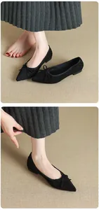 Detail view of elegant black pointed-toe ballet flats with bow accent, worn on feet.