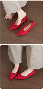 Close-up of red pointed-toe ballet flats with elegant bow detail on wooden floor