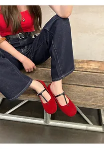 Close-up detail of red suede round-toe Mary Jane ballet flats with thin black straps.
