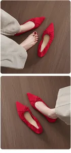 Detailed top view of elegant red suede ballet flats with bow detail on wooden floor