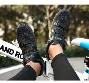 Close-up of black patterned cycling shoes with adjustable straps worn on a bicycle.