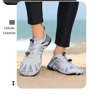 Gros plan de chaussures de plage gris clair respirantes portées sur une plage de sable fin.