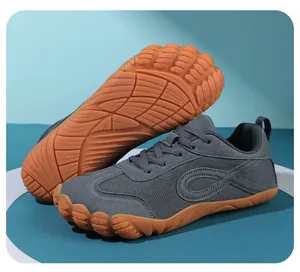 Dettaglio di scarpe sportive a piedi nudi grigie con suole in gomma arancione antiscivolo.