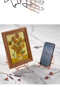 Dettaglio di eleganti supporti in metallo oro rosa per cornici e smartphone moderni.
