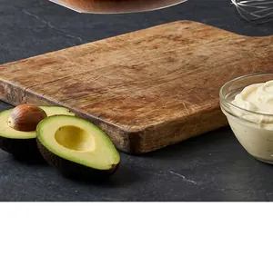 Rustic large wooden pizza serving board with natural grain on a dark kitchen stone counter