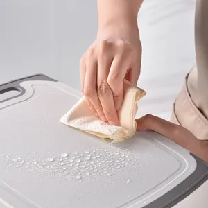 Person wiping water from a textured gray kitchen cutting board with a paper towel