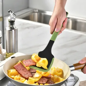 Heat-resistant green silicone spatula for non-stick pans used in home kitchen cooking scene.