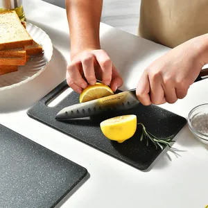 Black marble pattern plastic cutting board set of 3 being used to slice fresh lemons