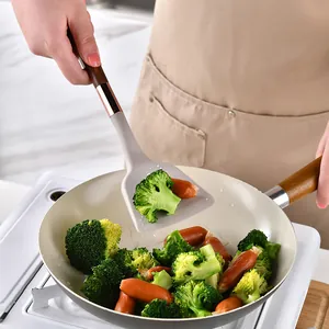 Siliconen spatel met houtlook handvat gebruikt in een pan met broccoli en worstjes