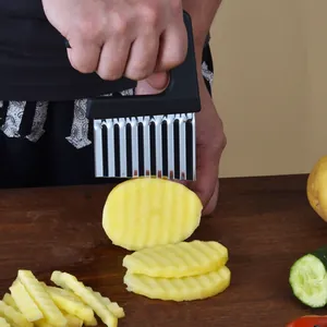 Coupe-frites ondulé en acier inoxydable tranchant des pommes de terre sur une planche
