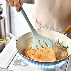 Mint green silicone slotted spatula with stainless steel handle used for cooking.
