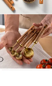 Close-up of four stainless steel measuring spoons with ergonomic wooden handles.