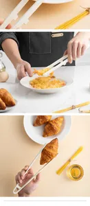 Detail view of white heat-resistant silicone tongs with stand clamping a croissant.