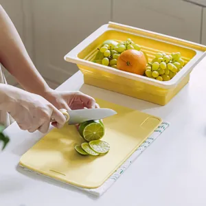 Action shot of slicing a lime on a yellow foldable cutting board with strainer basket.