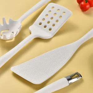 White integrated silicone kitchen utensil set with silver hanging hooks on yellow background
