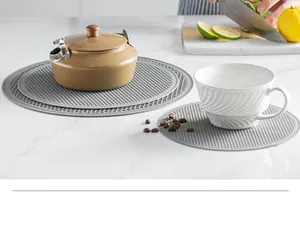 Close-up of grey silicone trivet mats used for teapot and cup in a kitchen setting.