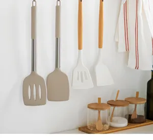 Détail de spatules en silicone et écumoires suspendus à un mur de cuisine