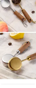 Detail of 14ml gold-plated and stainless steel measuring spoons with wooden handles.