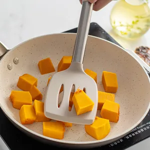 Spatule à fente en silicone avec manche en inox faisant sauter du potiron en poêle